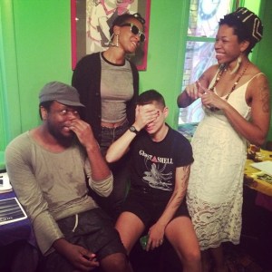 A laughing crew of zinesters making fun expressions in a room with bright green walls.