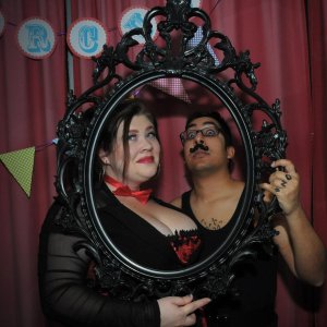 Two of The Wheelhouse zinesters, Lauren and Aus, posing behind an empty ornate black frame.